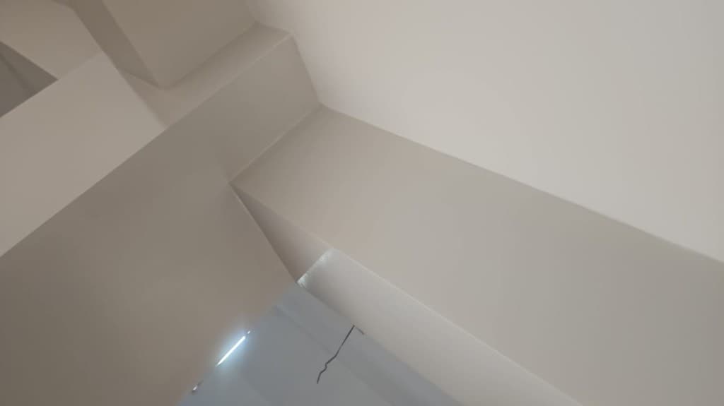 Close-up of freshly painted off-white ceiling beams and soffits with sharp, clean corners.